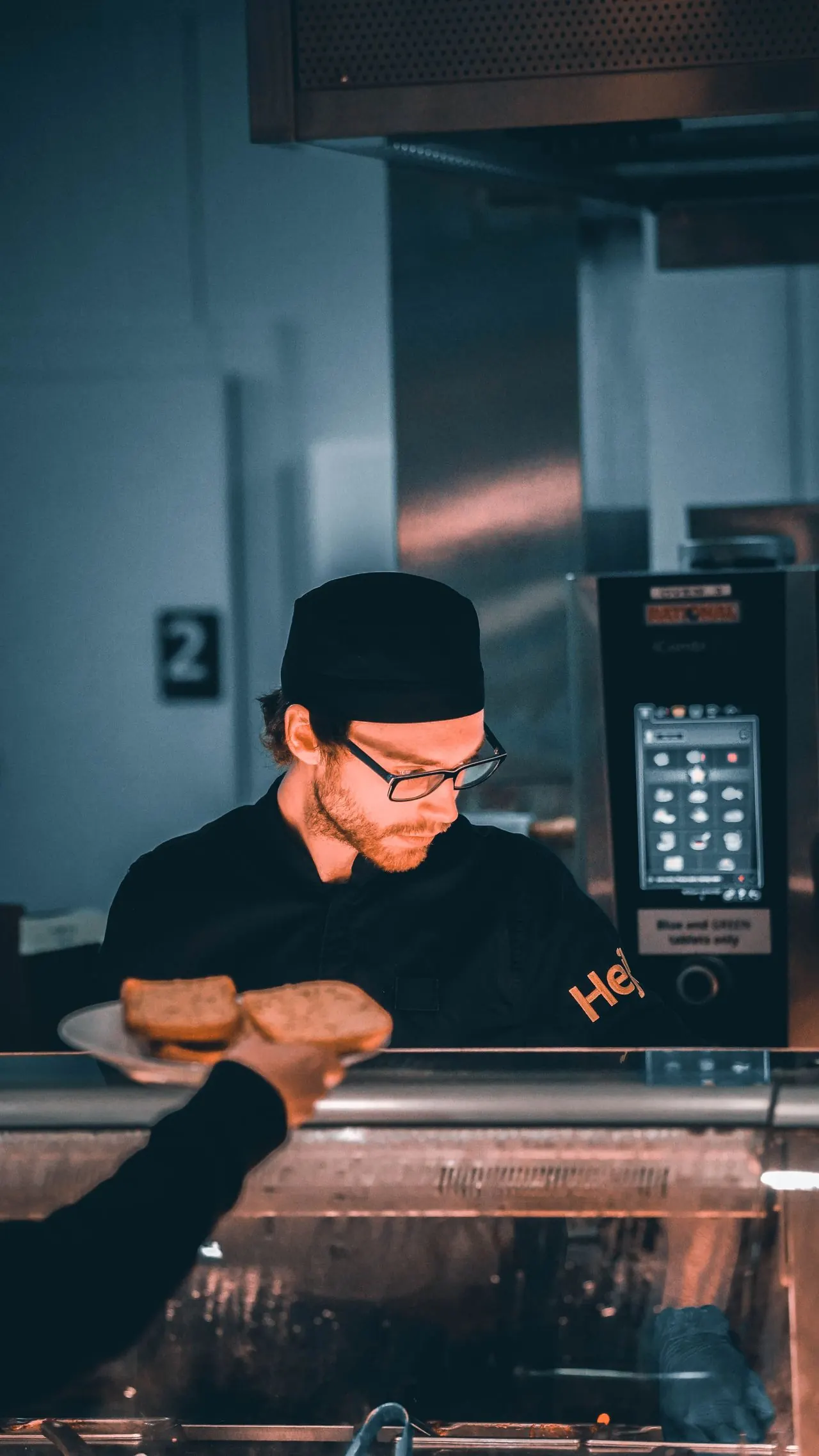 Un professionnel portant une toque et des gants travaille dans une cuisine professionnelle